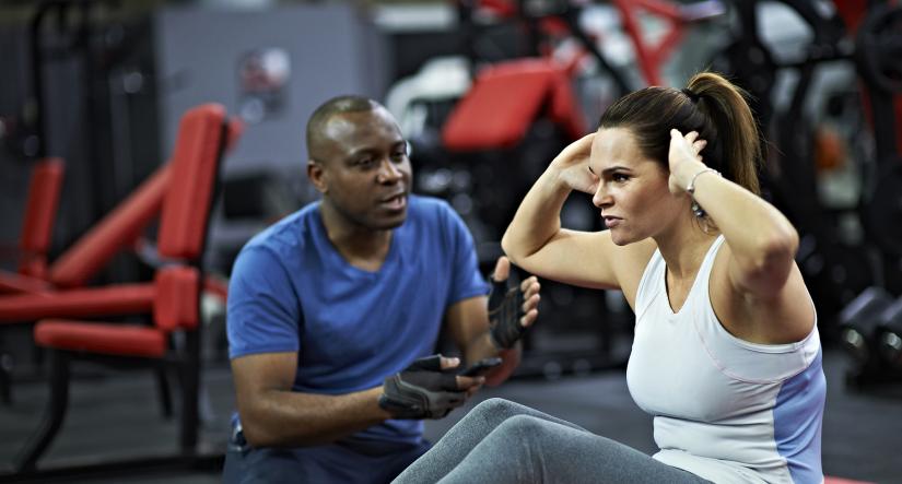 A personal trainer guides a woman doing sit ups