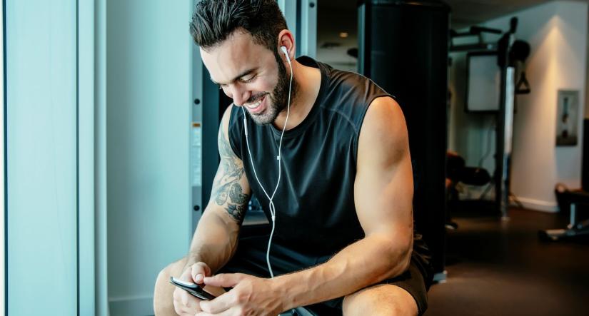 Man using his phone on an exercise machine.