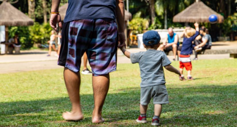 Father and son walking holding hands in the grass